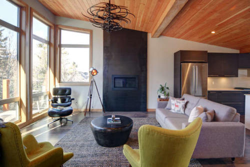 New construction Banff Canmore living room open concept hardwood floors wood contemporary industrial wood stairs metal railings stainless steel appliances steel fireplace wood roof feature white wood wall 