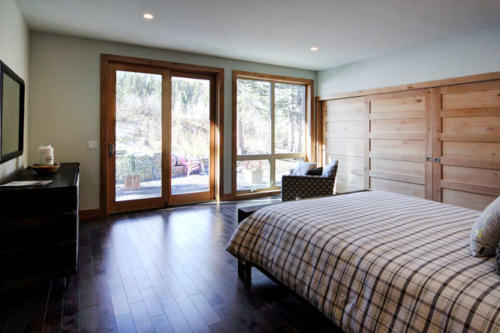 New construction Banff Canmore master bedroom room open concept hardwood floors wood contemporary industrial wood stairs metal railings wood barn doors