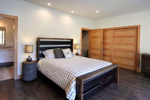 New construction Banff Canmore master bedroom room open concept hardwood floors wood contemporary industrial wood stairs metal railings wood barn doors 