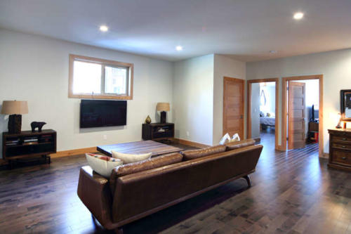 New construction Banff Canmore family room open concept hardwood floors wood contemporary industrial wood stairs metal railings wood barn doors 