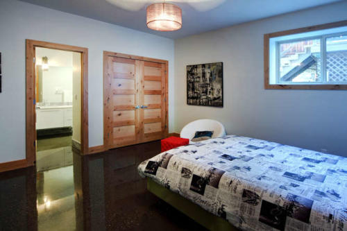 New construction Banff Canmore master bedroom room open concept polished concrete  floors wood contemporary industrial wood stairs metal railings wood barn doors 