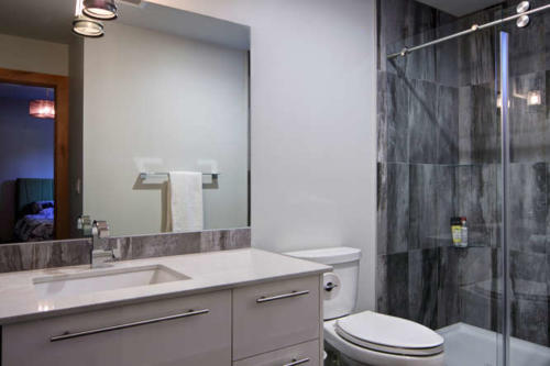 New construction Banff Canmore bathroom open concept polished concrete floors wood contemporary industrial wood stairs metal railings wood barn doors grey tile  