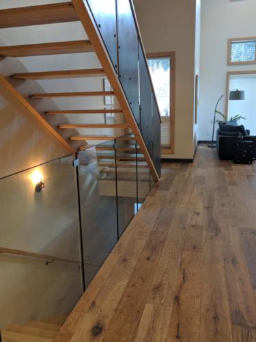 New construction Banff Canmore open concept hardwood floors wood panel ceiling timberframe wood contemporary industrial design glass railings wood metal stairs steel baseboards