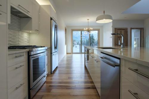 New construction Canmore new construction kitchen hickory wood floors glass railings white kitchen stainless steel appliances contemporary industrial design 