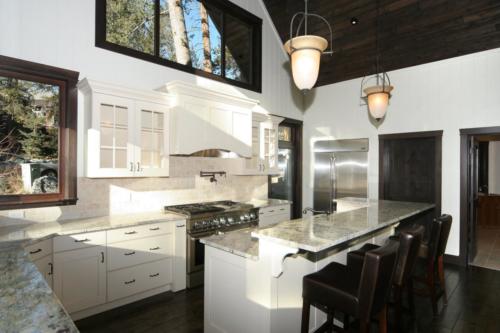 New construction Banff Canmore white wood kitchen open concept hardwood floors timberframe wood contemporary industrial wainscoting walls stone counter tops stainless steel appliances 