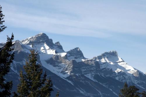 New construction Banff Canmore living room open concept hardwood floors timberframe wood contemporary industrial wainscoting walls wood stairs metal railings mountain views 
