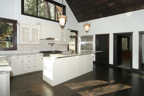 New construction Banff Canmore white kitchen open concept hardwood floors timberframe wood contemporary industrial wainscoting walls wood stairs metal railings stainless steel appliances stone counter tops