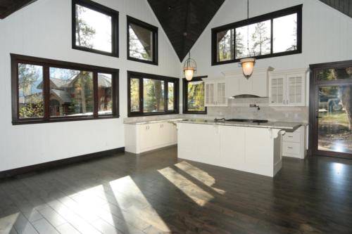 New construction Banff Canmore white kitchen open concept hardwood floors timberframe wood contemporary industrial wainscoting walls wood stairs metal railings stainless steel appliances stone counter tops