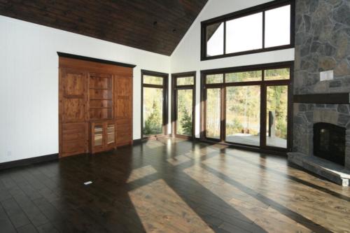New construction Banff Canmore living room open concept hardwood floors timberframe wood contemporary industrial wainscoting walls wood stairs metal railings stainless steel appliances stone fireplace 
