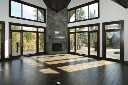 New construction Banff Canmore living room open concept hardwood floors timberframe wood contemporary industrial wainscoting walls wood stairs metal railings stainless steel appliances stone fireplace 