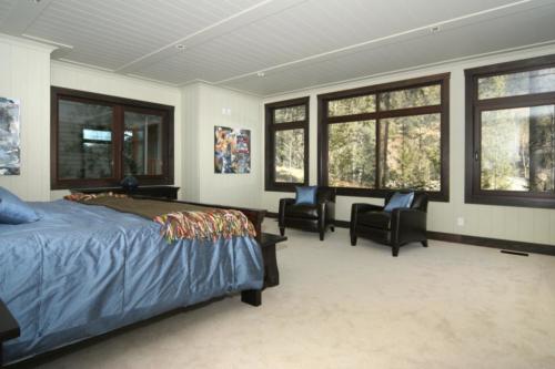 New construction Banff Canmore master bedroom open concept hardwood floors timberframe wood contemporary industrial wainscoting walls wood stairs metal railings stainless steel appliances stone fireplace 