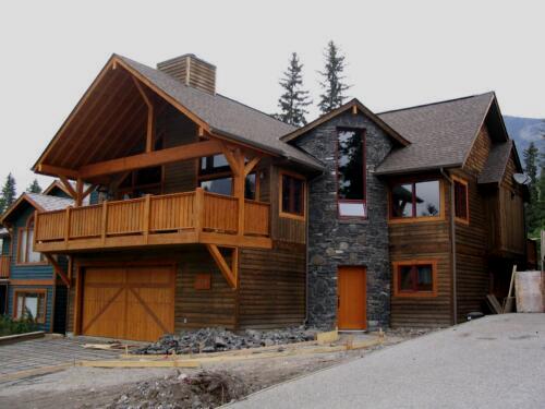 New construction Banff Canmore round stone wall open concept hardwood floors wood contemporary industrial wainscoting walls wood stairs metal railings stainless steel appliances stone fireplace spiral staircase