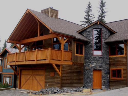 New construction Banff Canmore round stone wall open concept hardwood floors wood contemporary industrial wainscoting walls wood stairs metal railings stainless steel appliances stone fireplace spiral staircase