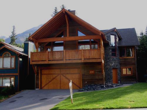 New construction Banff Canmore round stone wall open concept hardwood floors wood contemporary industrial wainscoting walls wood stairs metal railings stainless steel appliances stone fireplace spiral staircase