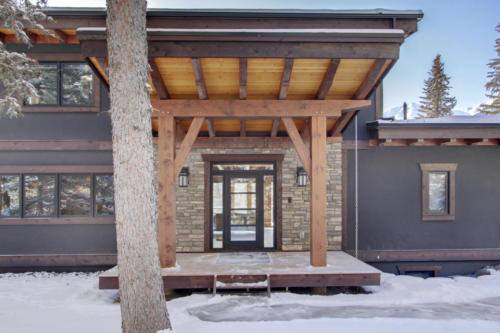 New construction Banff Canmore timberframe stone front entrance open concept hardwood floors wood contemporary industrial wood stairs metal railings wood barn doors 