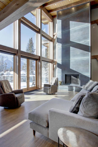 New construction Banff Canmore living room steel fireplace timberframe open concept hardwood floors wood contemporary industrial wood stairs metal railings wood barn doors 
