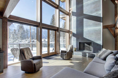 New construction Banff Canmore living room steel fireplace timberframe open concept hardwood floors wood contemporary industrial wood stairs metal railings wood barn doors 