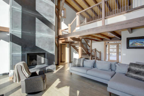 New construction Banff Canmore living room steel fireplace timberframe open concept hardwood floors wood contemporary industrial wood stairs metal railings wood barn doors loft 