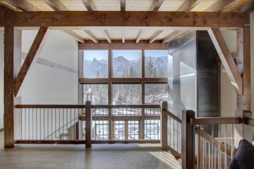 New construction Banff Canmore living room steel fireplace timberframe open concept hardwood floors wood contemporary industrial wood stairs metal railings wood barn doors loft 