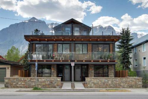 8th-Ave new construction Canmore rock fence industrial contemporary design steel and timber rooftop decks grass roof garage